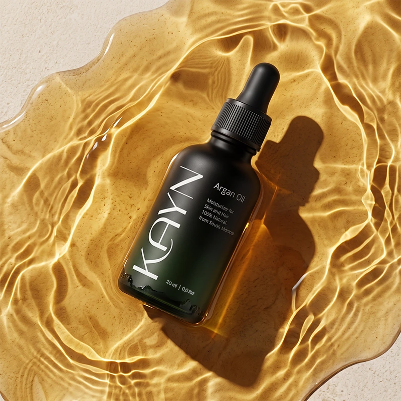 The 20ml Kayn Argan Oil bottle resting in a shallow pool of golden light.