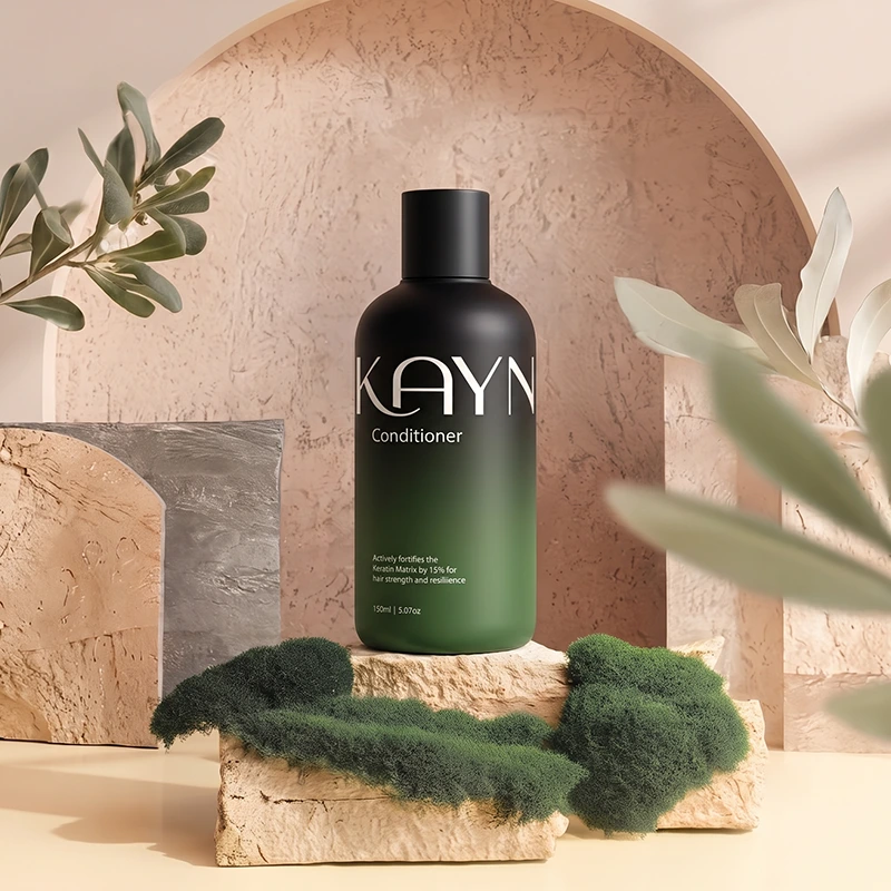 The 150ml Kayn Conditioner on a stone plinth with olive foliage and moss.
