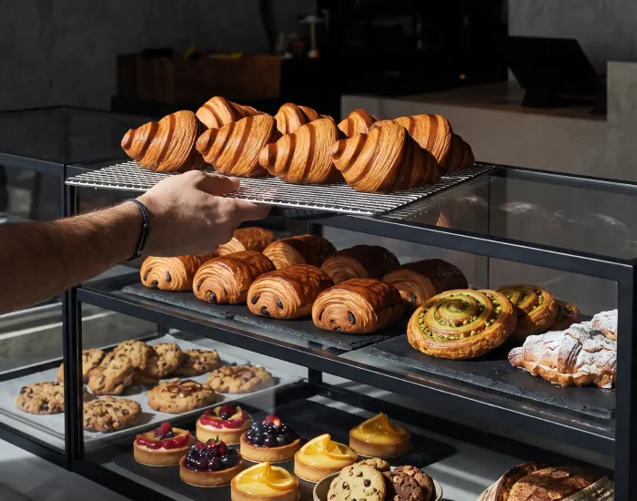 A baker lifting a tray of croissants from the NOBI display case